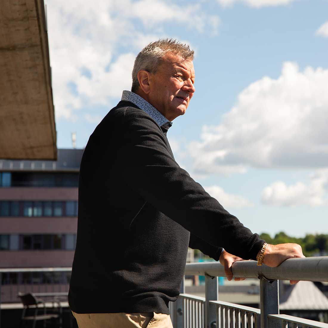 Thomas Engström står ute på en veranda och tittar på utsikt över staden