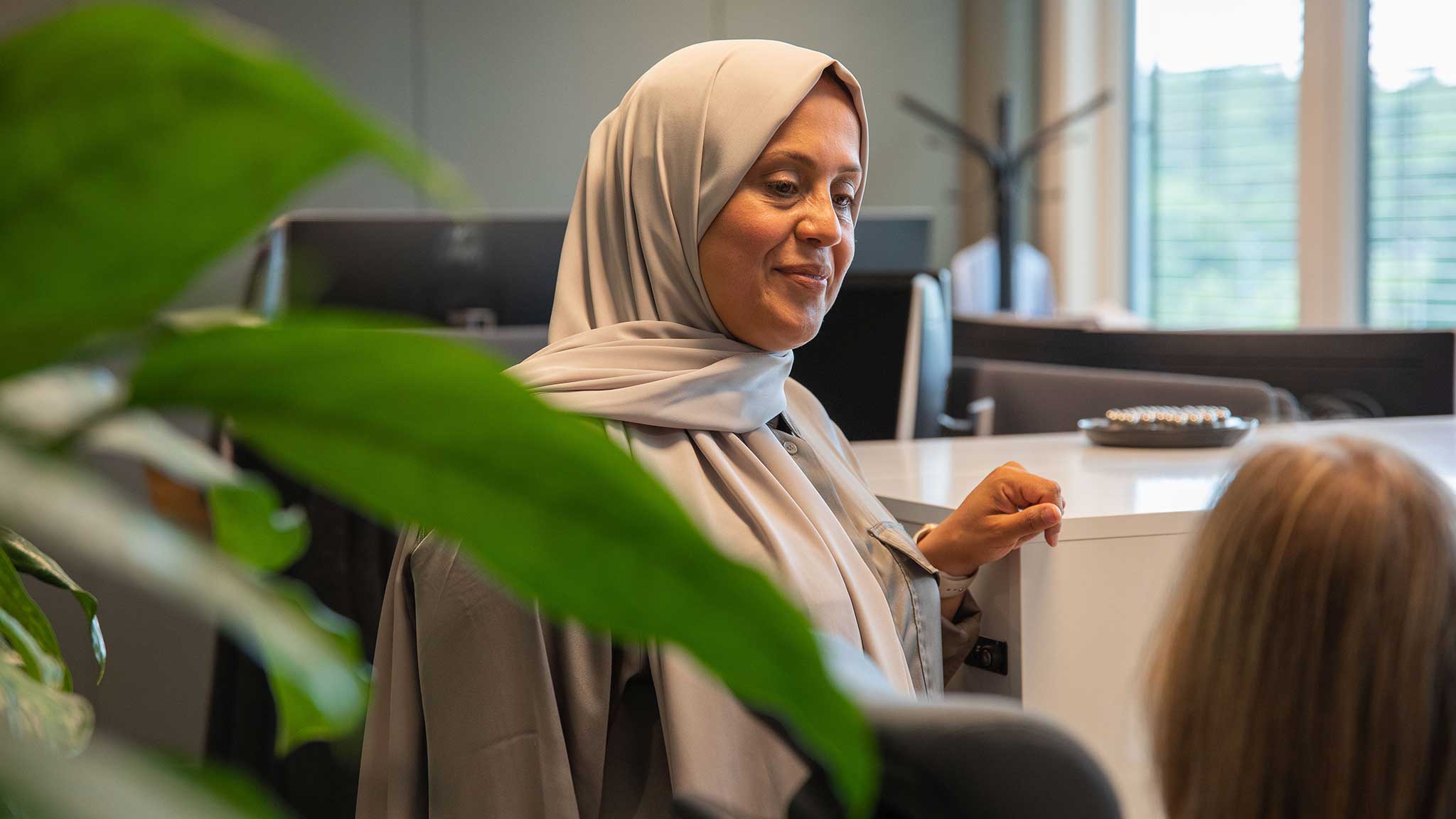 Asma Al-Hassani i samtal med kollega i ett kontorslandskap