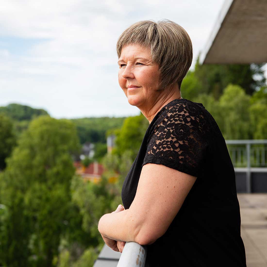 Ann Inger Hallager står ute på en veranda och tittar på utsikt över staden